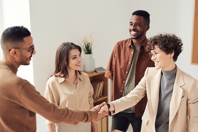 four people shaking hands inside someones apartment